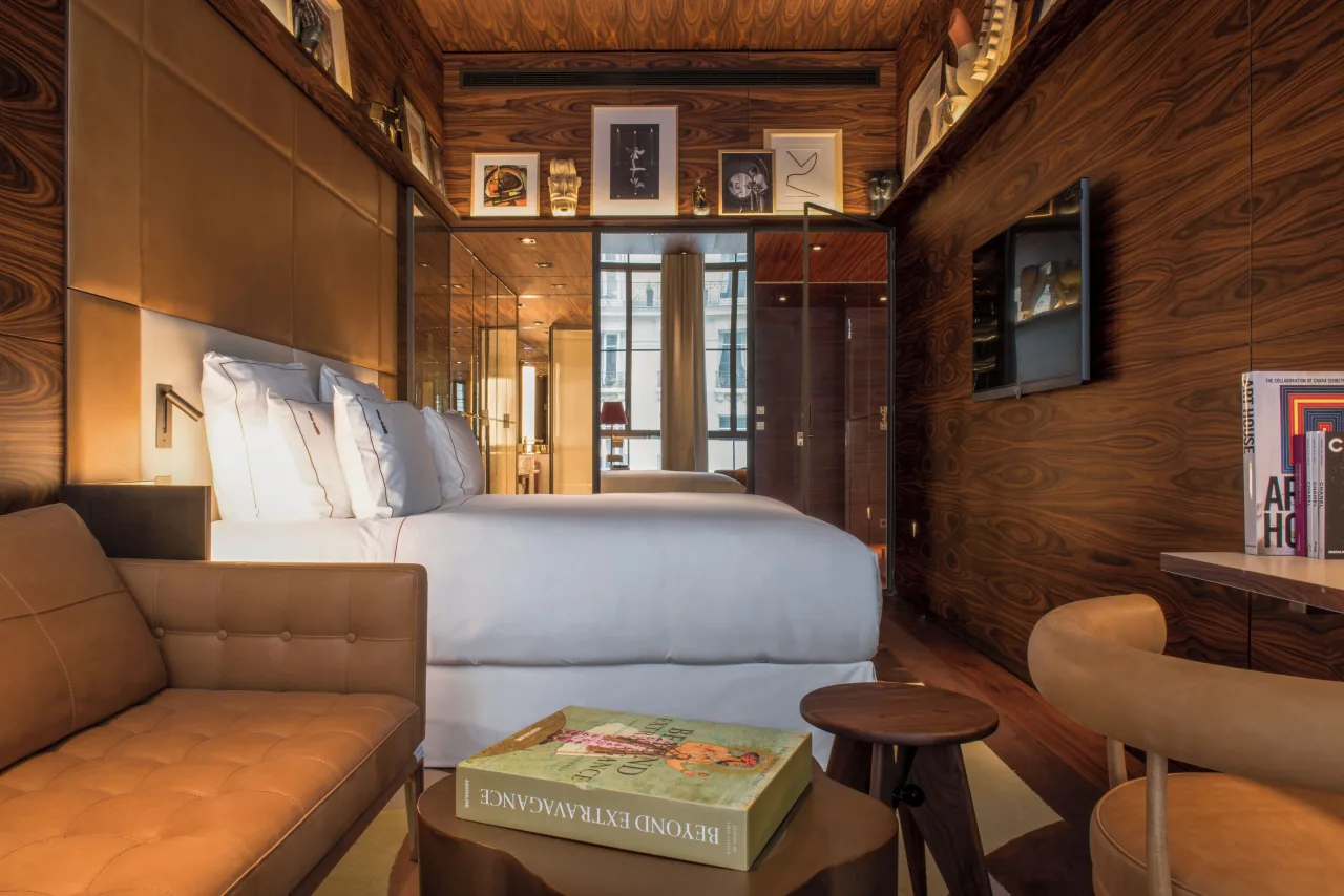 A bedroom panelled in wood, with books, a sofa and a bed
