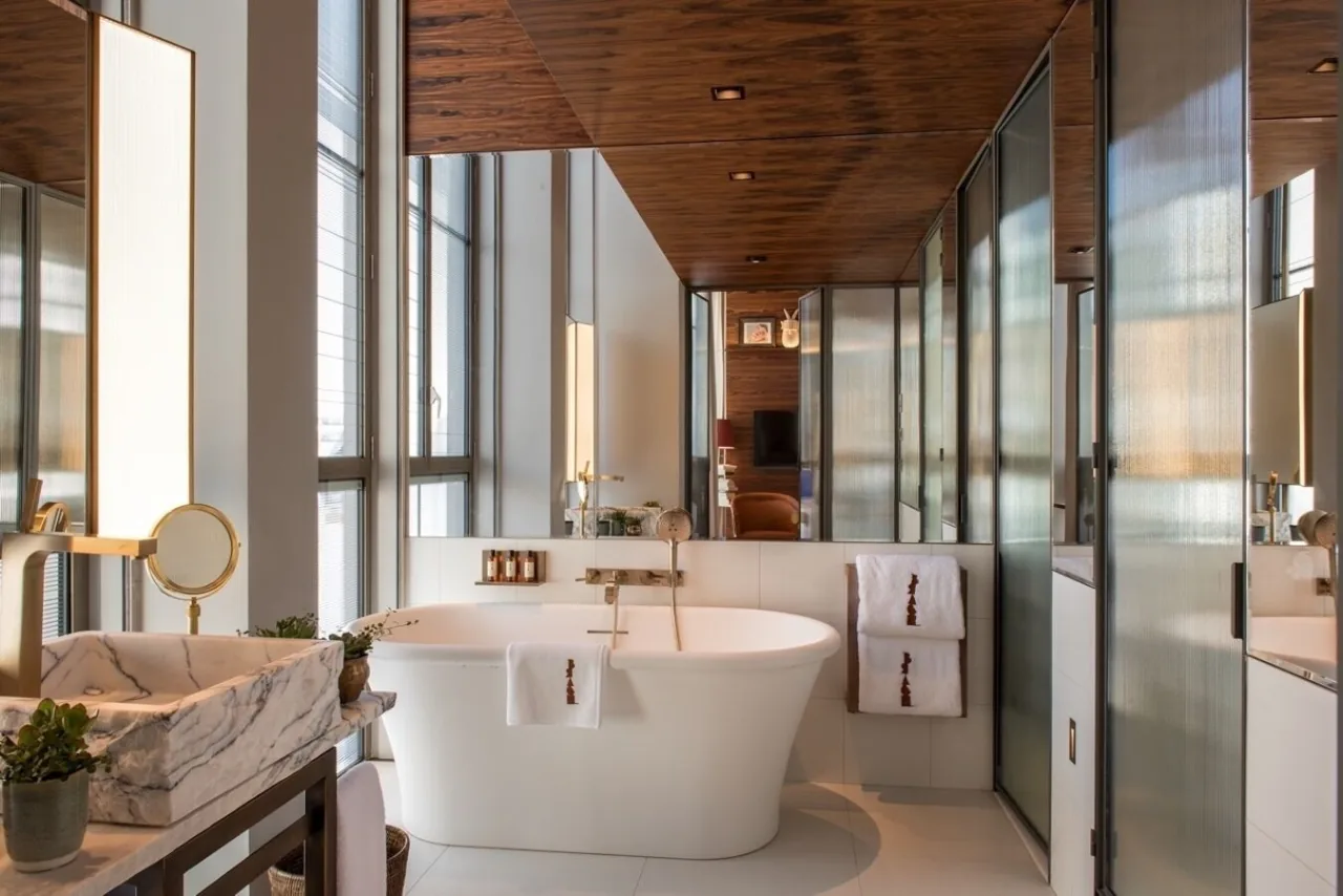 A bathroom with a freestanding bathtub between glass partitions and wood