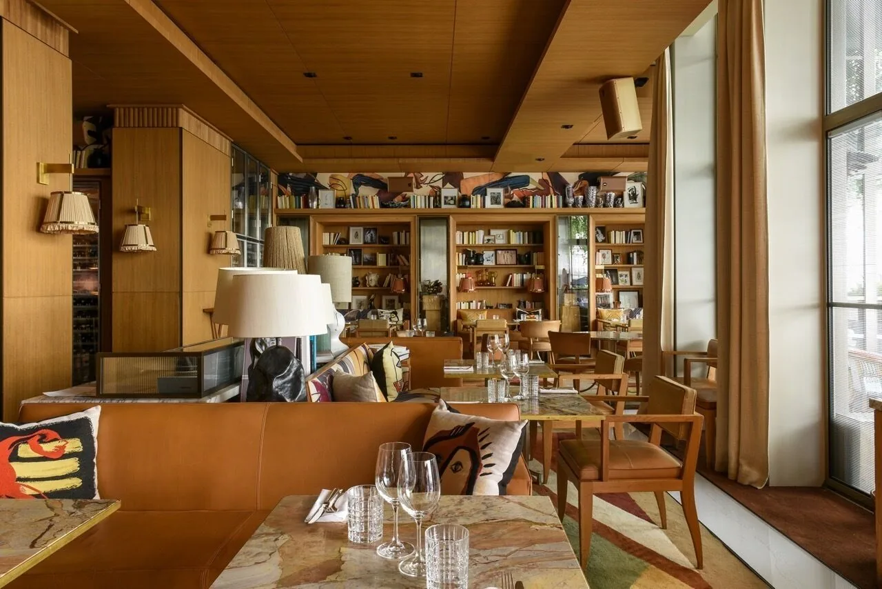 A dining room lined with bookshelves, tables laid with glasses