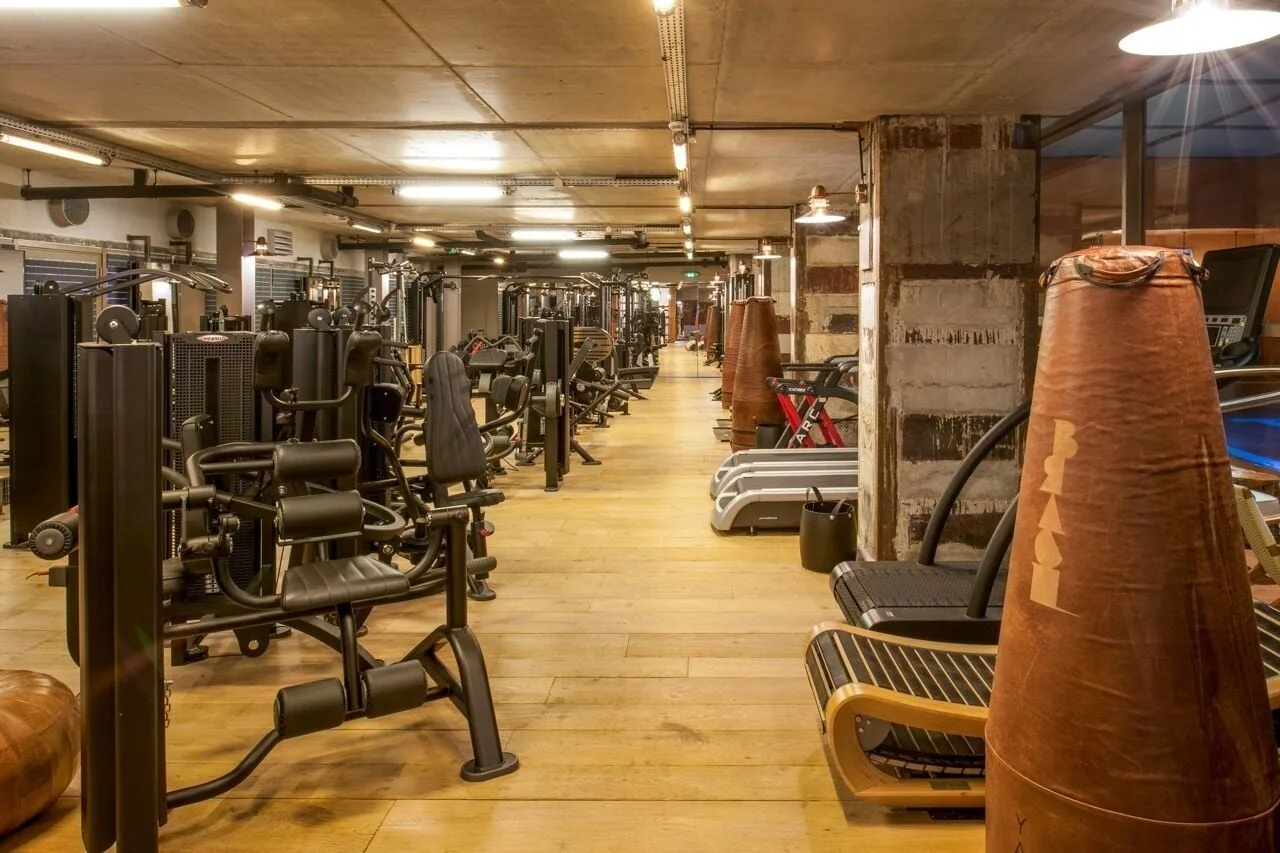 Rows of training machines on a wooden floor under industrial lamps