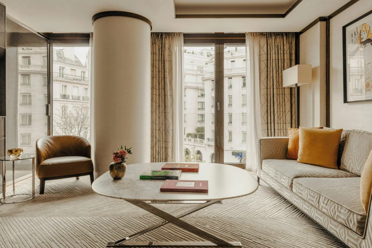 A living room with a pale sofa, leather armchairs, an oval coffee table and a round column by the windows