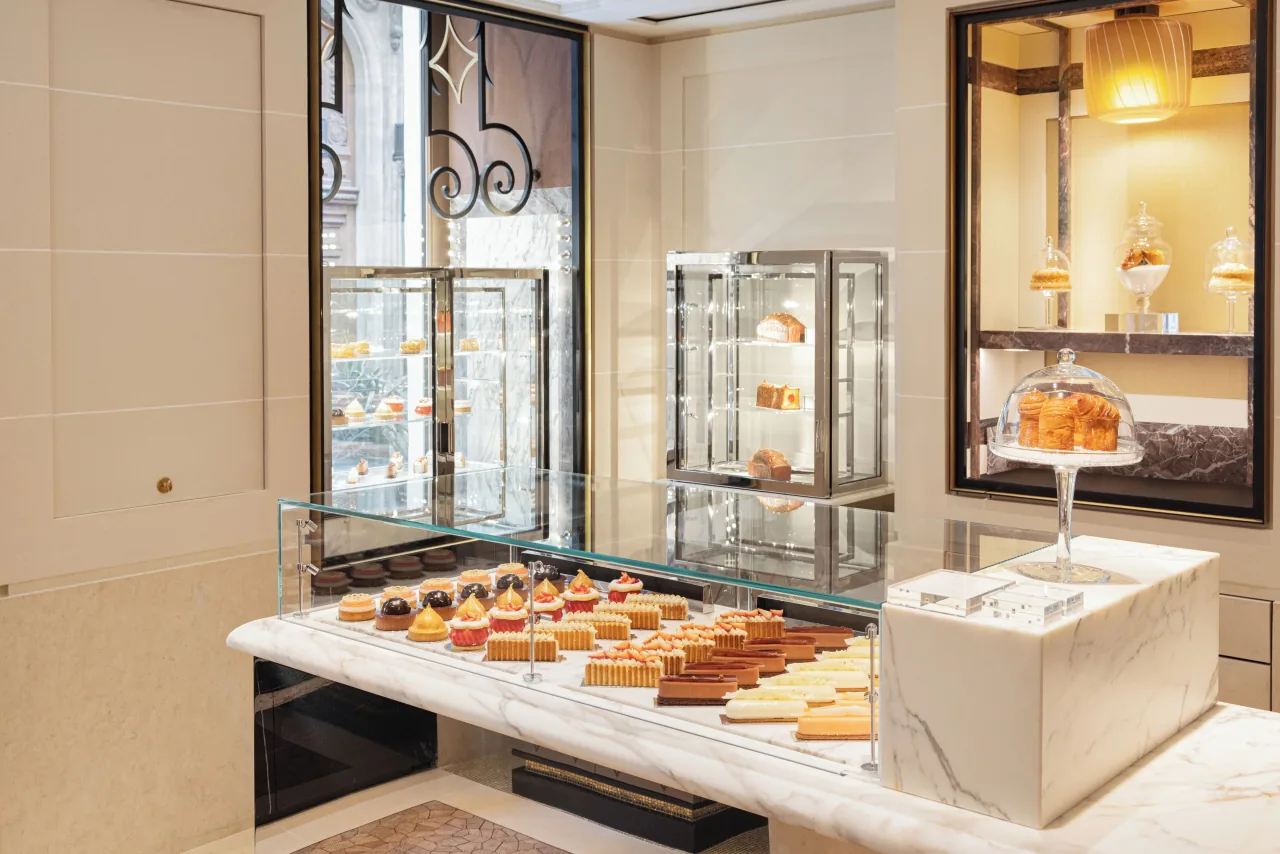 Un comptoir de marbre, des rangées de pâtisseries sous verre et une vitrine