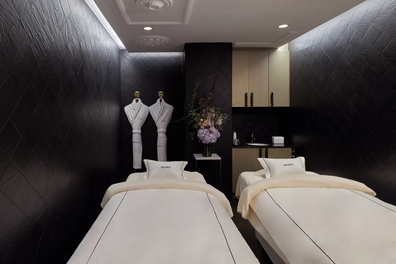 Une cabine de soins, deux tables de massage, deux peignoirs blancs et des murs sombres