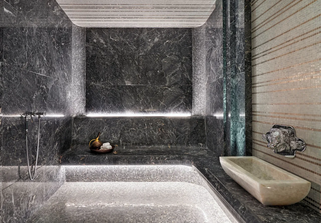 Un hammam de marbre gris, vasque de pierre et mur de mosaïque