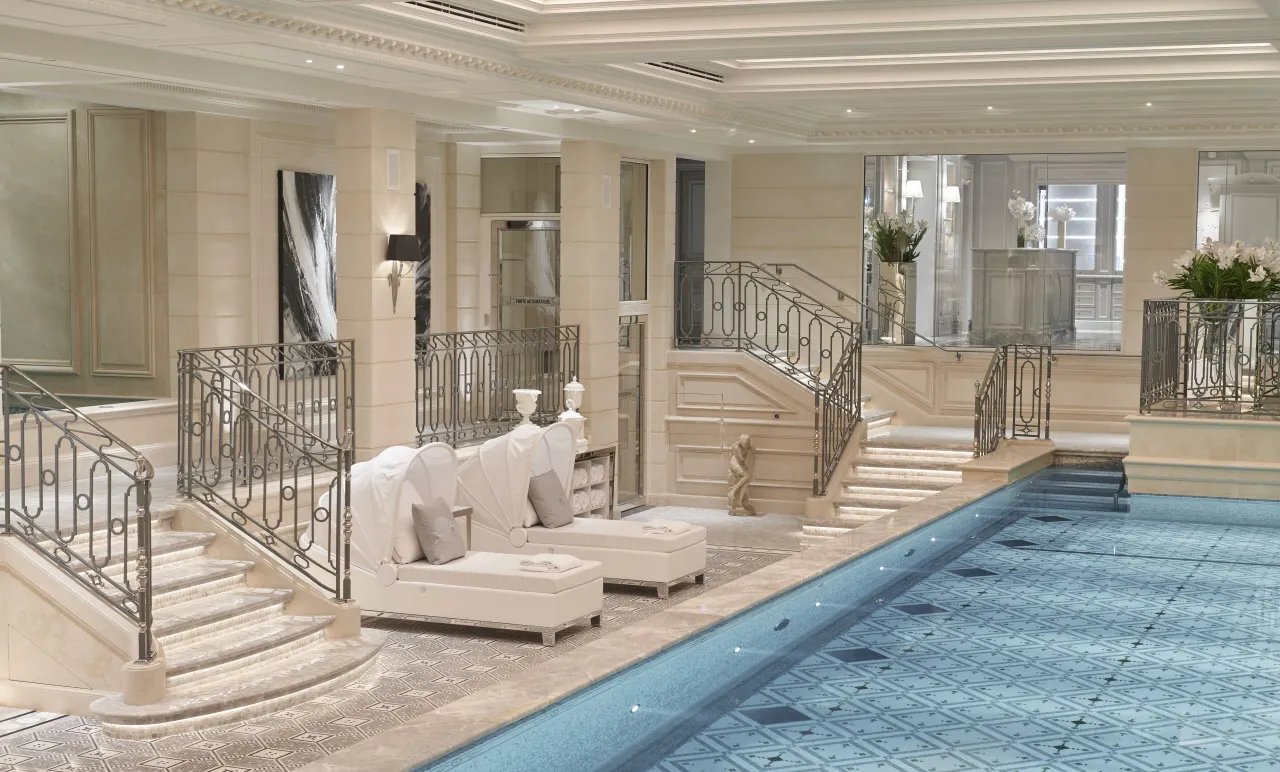 Le bout de la piscine intérieure, deux escaliers courbes et des chaises longues blanches