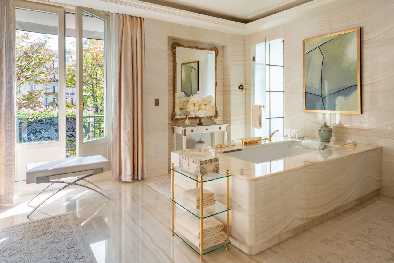 Une salle de bains de marbre, baignoire, miroir et porte-fenêtre sur un balcon
