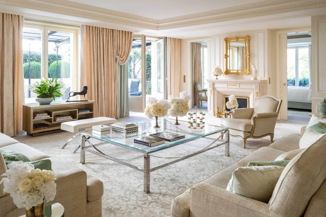 Le salon d’une suite, canapés, table basse en verre, cheminée et portes-fenêtres sur une terrasse