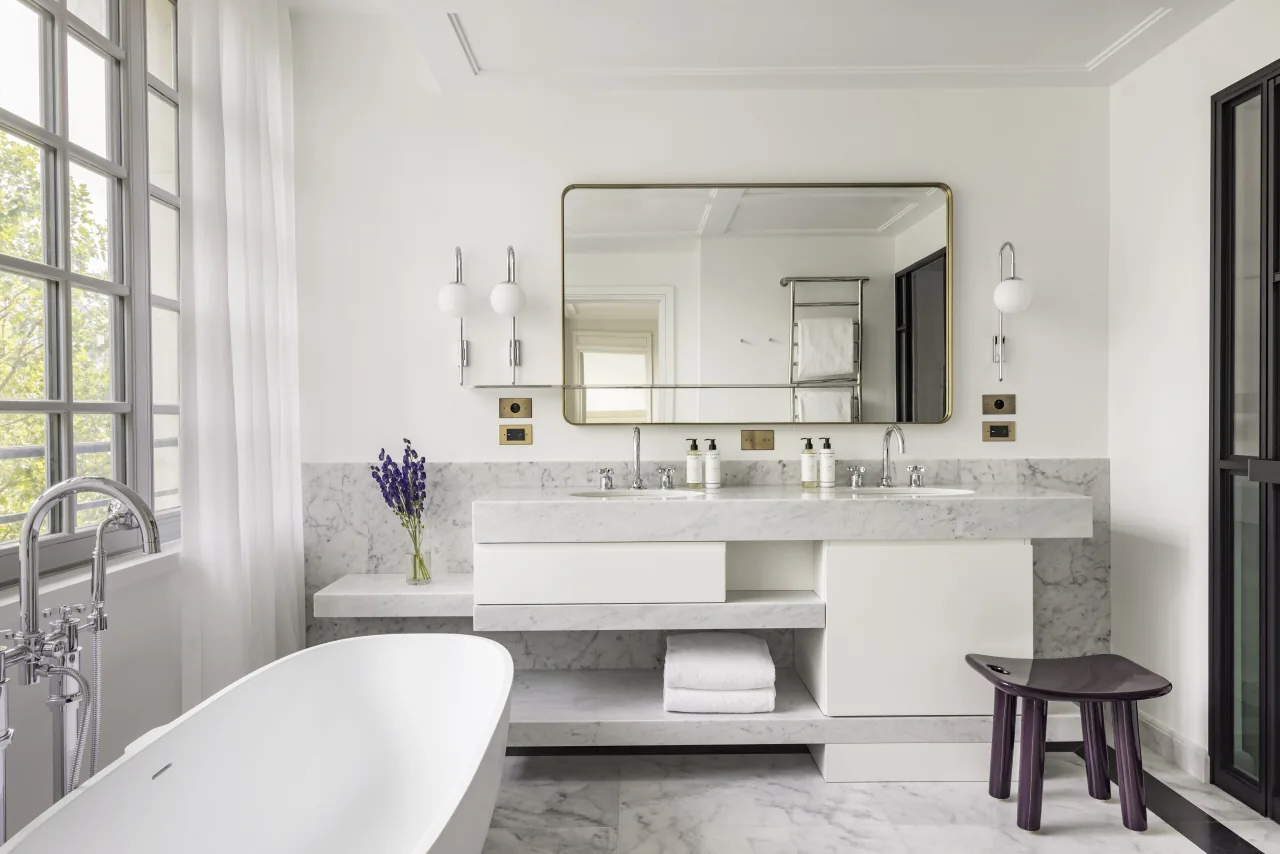 Une salle de bains de marbre blanc, une baignoire îlot et un double lavabo