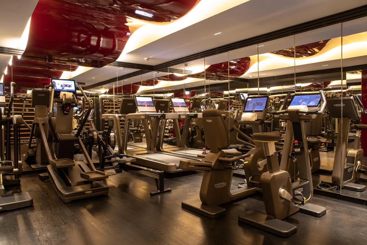 Un studio fitness, des tapis de course et des machines sous un plafond laqué rouge
