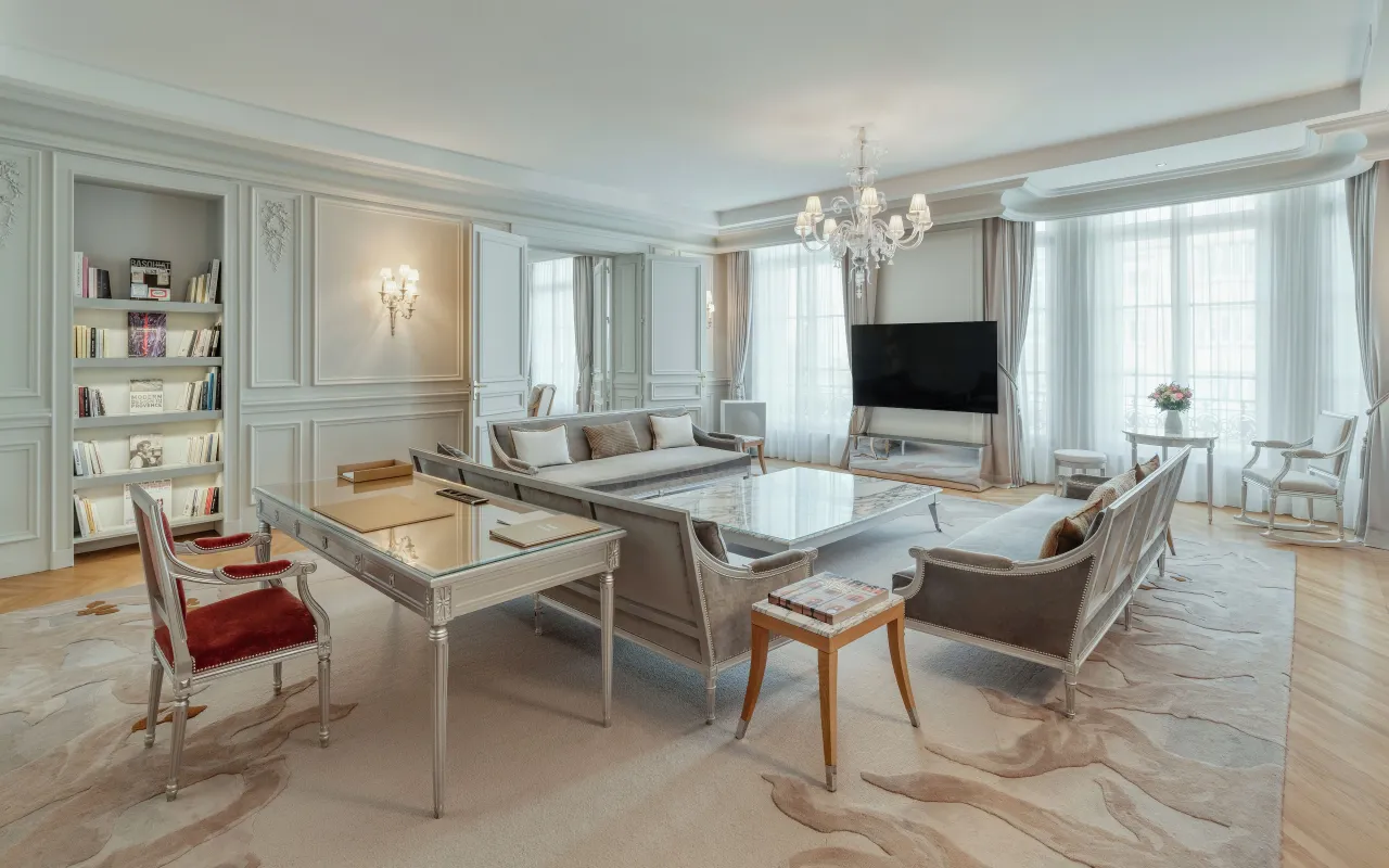Le séjour d’une suite avec bibliothèques, table à manger en miroir, canapés et lustre