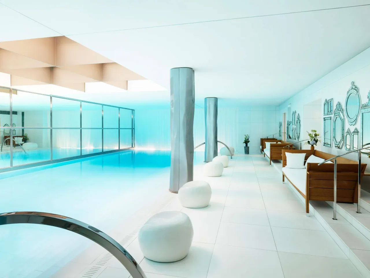 La piscine intérieure du spa du Royal Monceau, son eau claire bordée de colonnes, de sièges blancs et de panneaux de miroirs