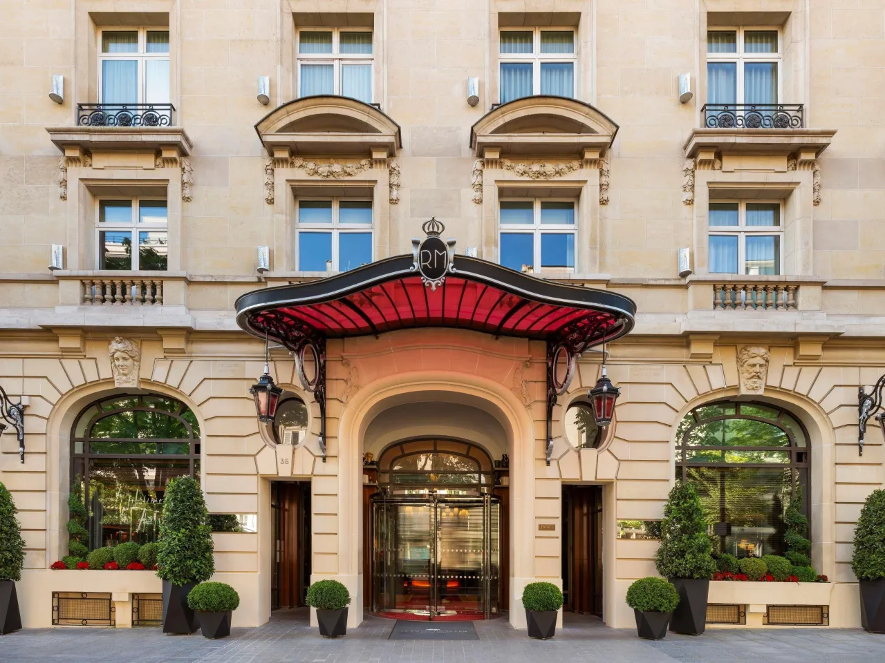 La façade en pierre du Royal Monceau, avenue Hoche, avec sa marquise rouge, ses lanternes et ses arbustes taillés