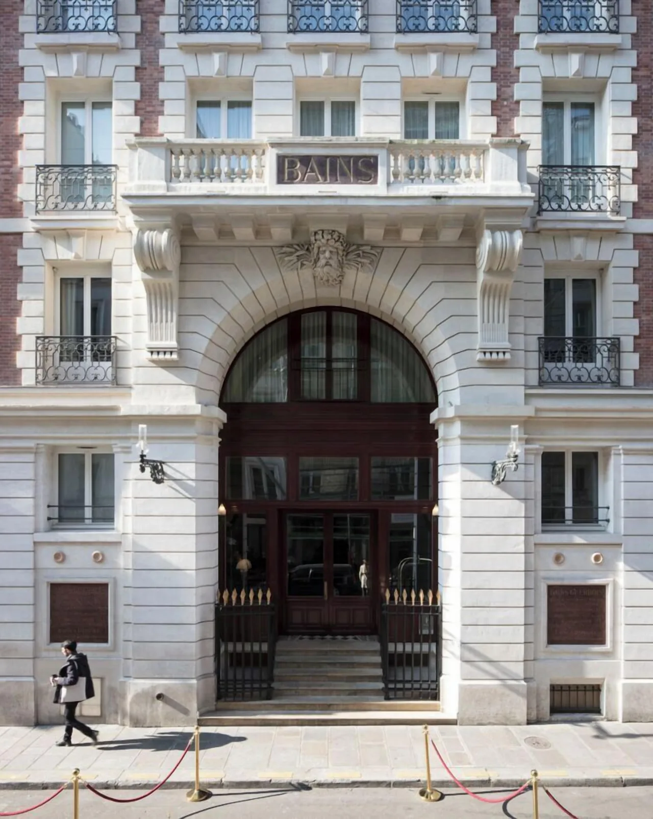 A pale stone façade with wrought-iron balconies and a tall arched doorway