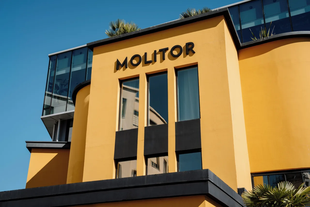 Une façade Art déco jaune portant le nom MOLITOR en lettres noires, sous un ciel bleu