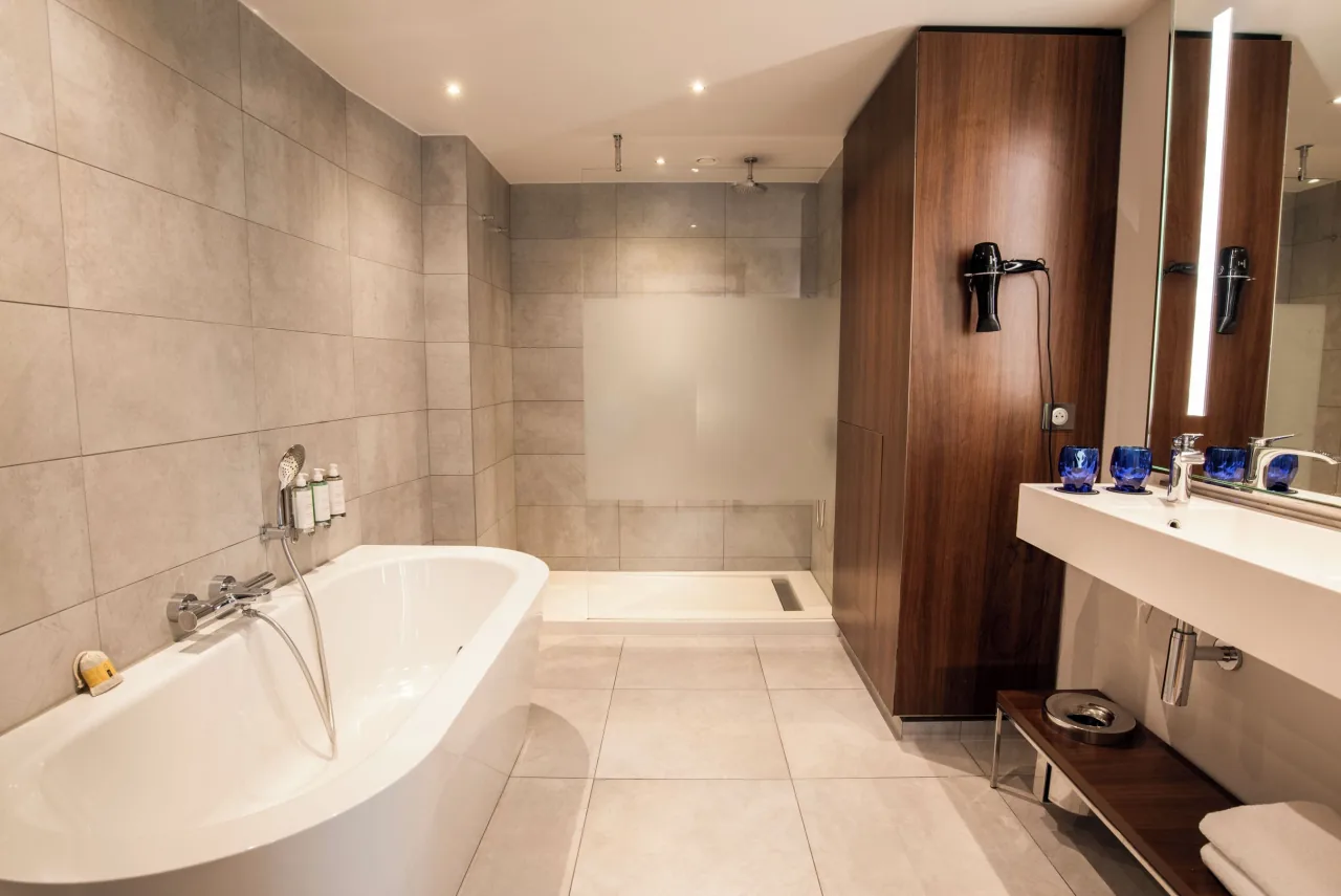 Une salle de bains, une baignoire îlot, une douche à l’italienne, du bois et de la pierre claire