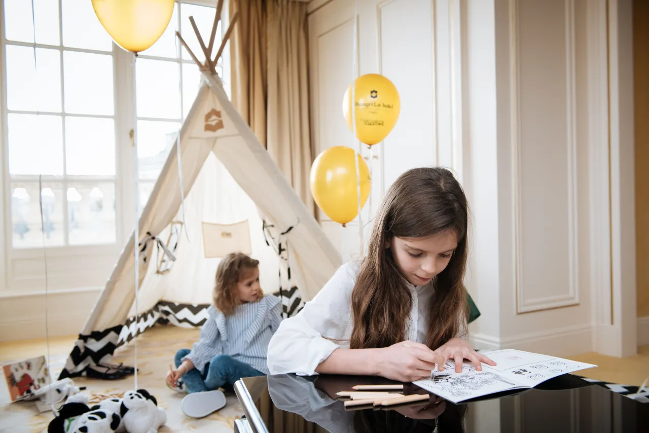 Two children playing in a room set up with a tepee tent and balloons