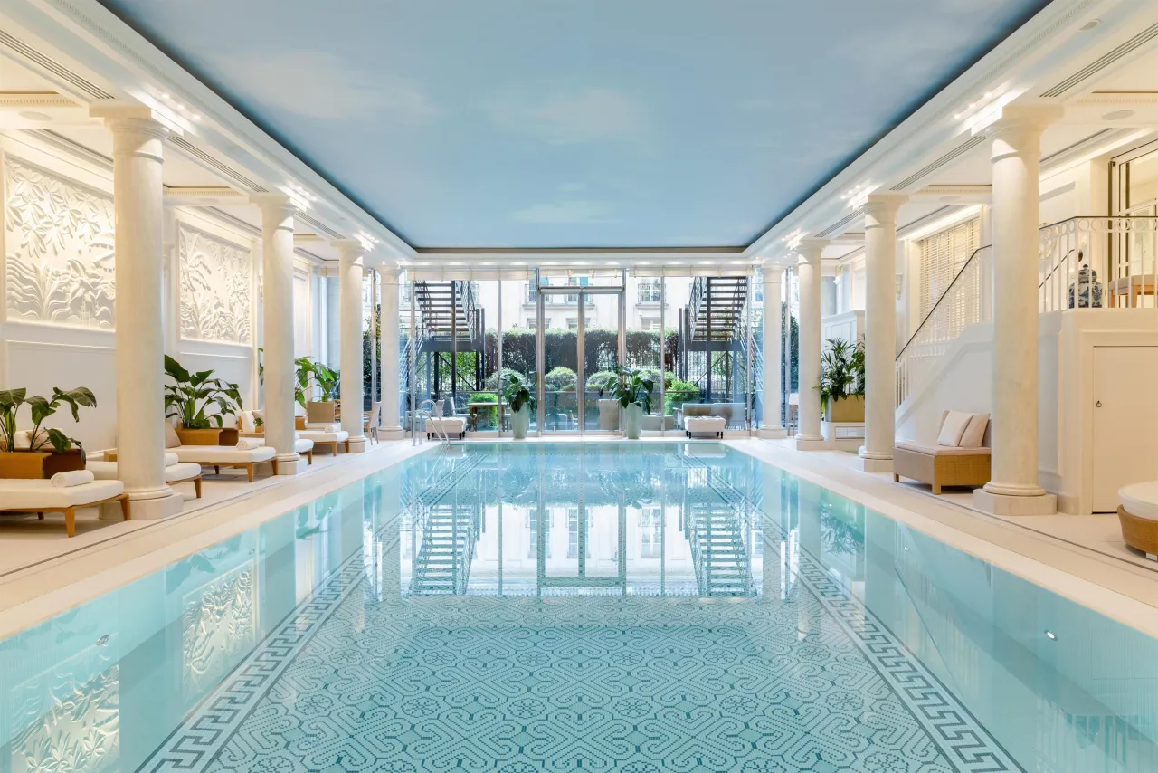 The spa swimming pool with a mosaic floor, columns, loungers and a glass wall at the far end